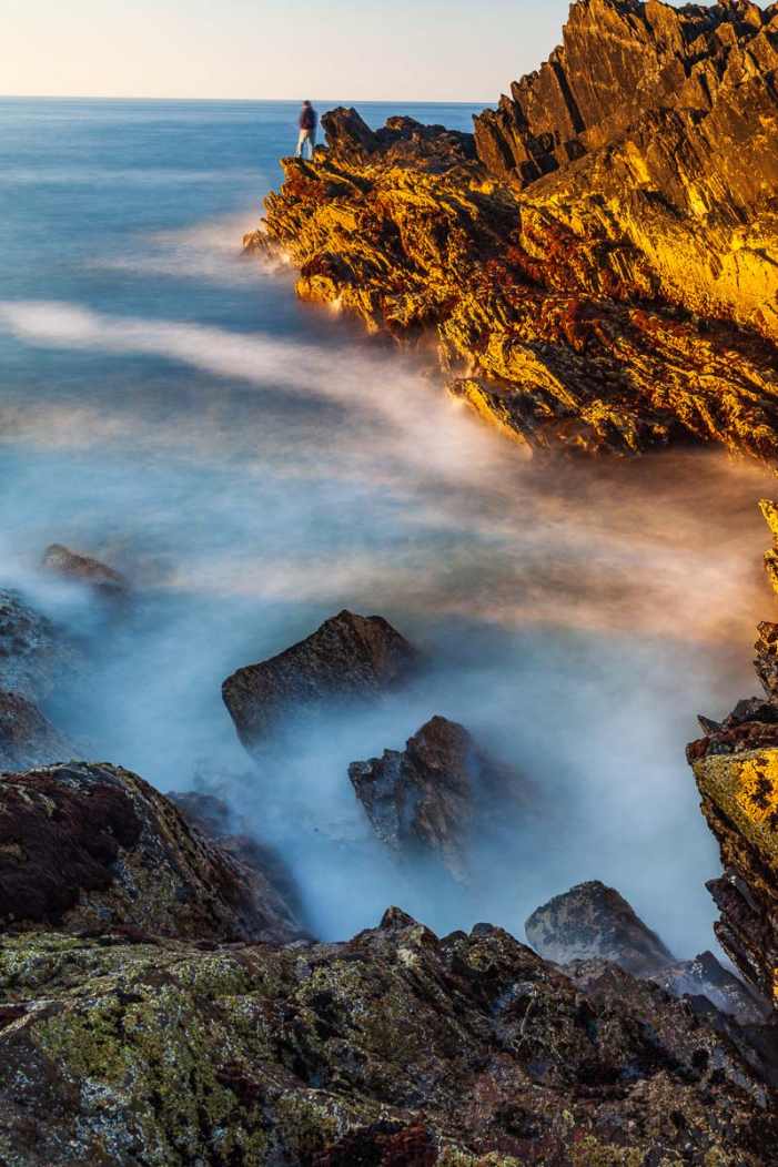 Küstenlandschaft mit Gezeitentümpeln, PEin Angler auf den gewaltigen Felsen. Portsoy, Schottland, Langzeitaufnahmen mit einem 1000 fach Graufilterortsoy, Schottland