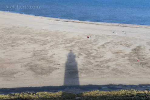 Der Schatten des Leuchtturms auf dem weiten Strand