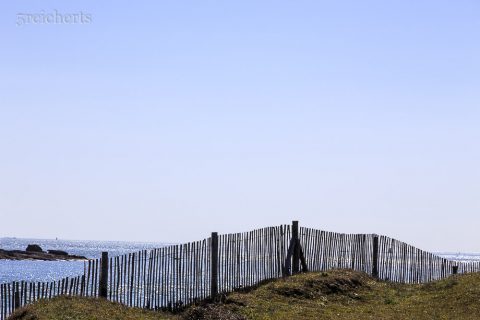 Strandzaun und gleißendes Meer