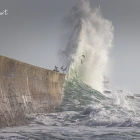 Eine Welle trifft die Hafenmauer in Lesconil