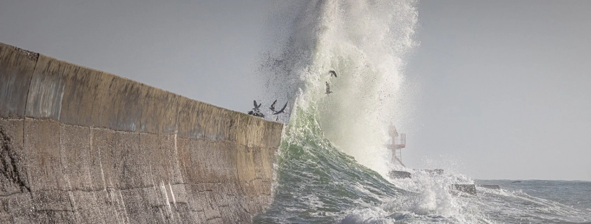 Eine Welle trifft die Hafenmauer in Lesconil